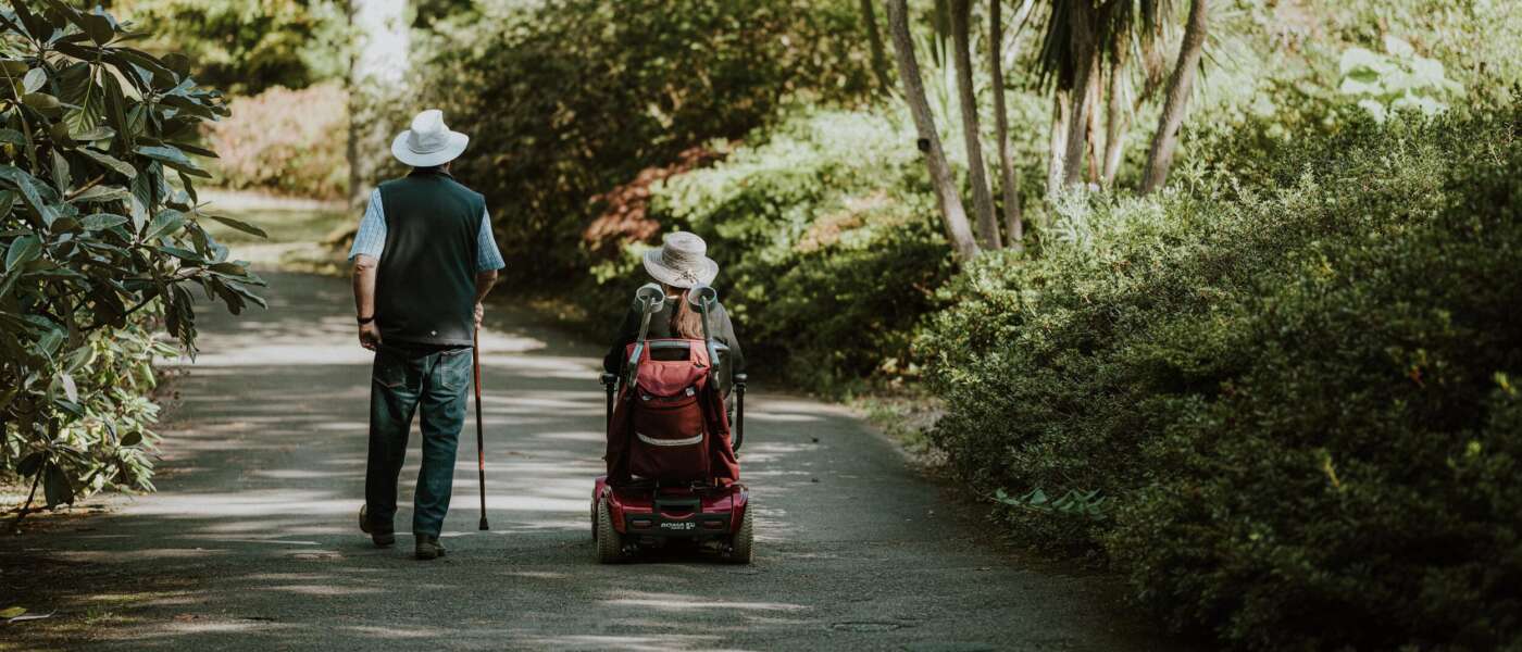 Two older adults together on a lush forest path